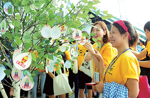 학생들이 종이로 만든 열매에 자신의 꿈과 희망을 적어 행사장 로비 가운데에 있는 희망나무에 달고 있다.