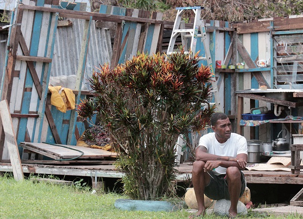 부서진 집 앞에서 넋을 잃고 앉아있는 주민.