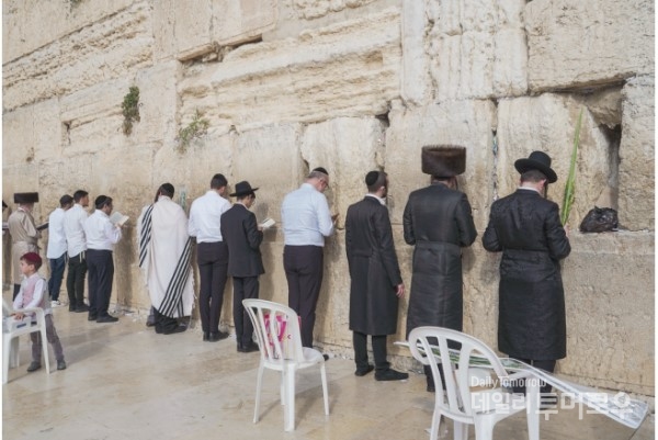 통곡의 벽에서 기도하는 유대인들. 모든 남자는 모자나 키파를 반드시 써야 한다. 하나님께 바라는 기도의 내용을 쪽지에 적어 돌 틈 사이에 끼워넣는다.